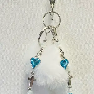 Handcrafted hope keychain/phonecharm/bagcharm with blue cat eye beads and blue resin beads. Silver placed spacers and cross.  Small white Pom Pom to finish a classy look. Two split rings attached with hook closure for attachment. Phone card attachment.