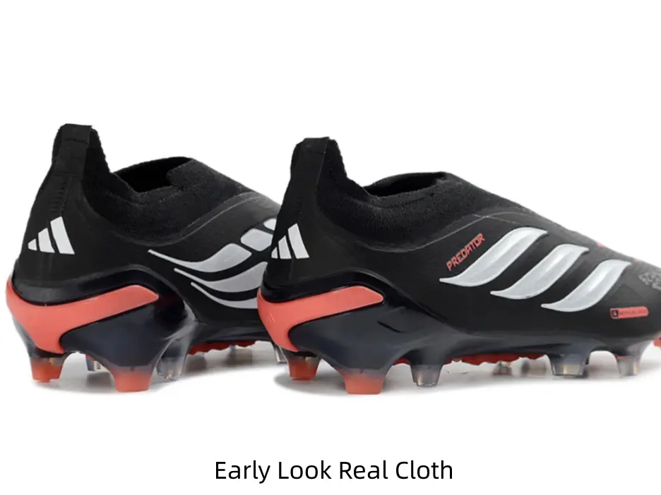 Sleek black laceless soccer cleats with silver stripes & orange heel accents, speed-focused match boots